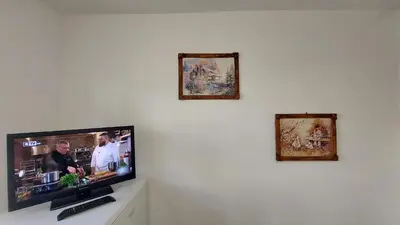 a flat screen tv on a white wall with three pictures at 3 Rooms Apartment, Top Center, 1st Floor Flat, AUBG, WiFi, PC i5 SSD, Tablet, AndroidMiTvBox, 3 LED TVs 200 Channels, Long Terrace, Self-Easy-Late Check-in, Stay Before Greece in Blagoevgrad