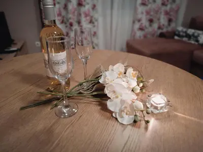 a table with a bottle of wine and glasses and flowers at Вила Ибър село Радуил in Raduil