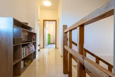 a hallway with a book shelf and a staircase at Вила Ибър село Радуил in Raduil