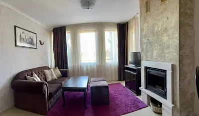 a living room with a couch and a tv at Гранд Манастира частен апартамент in Pamporovo