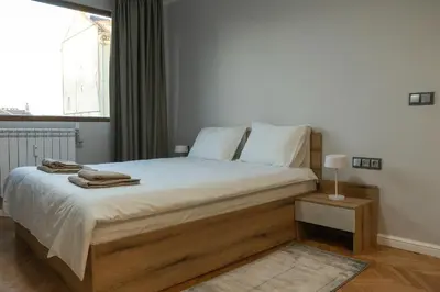 a bedroom with a bed with white sheets and a window at Jasmine Central Apartment in Sofia
