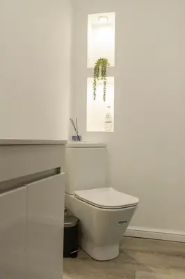 a white bathroom with a toilet and a window at Jasmine Central Apartment in Sofia