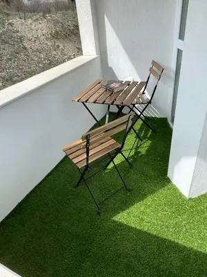 a table and chair on a balcony with green grass at Barceló Apartment Velingrad in Velingrad