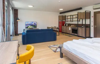 a living room with a blue couch and a kitchen at Complex Gallery Vitosha **** in Sofia