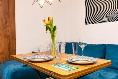 a wooden table with two plates and a vase with flowers at 'Little Little' House in the town CENTER & PARKING in Plovdiv