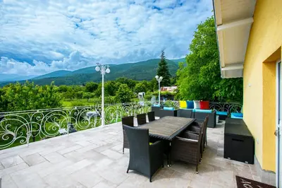 a patio with a table and chairs on a balcony at Къща за гости Кала in Patalenitsa