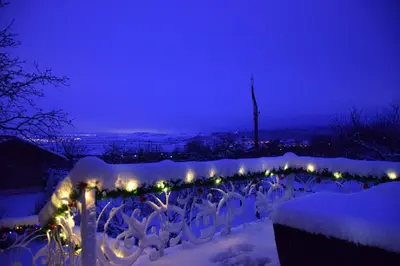 a fence covered in snow at night with lights at Къща за гости Кала in Patalenitsa