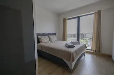 a bedroom with a bed with a large window at Green Eyes Apartments in Sofia
