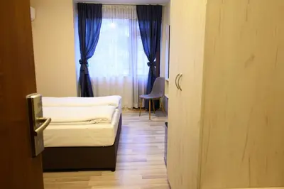 a room with a bed and a window with blue curtains at Hotel Leda in Sofia