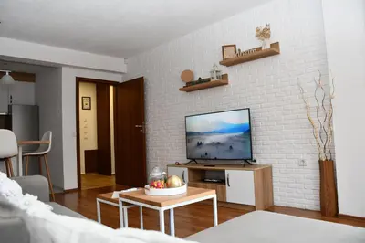 a living room with a tv on a white brick wall at Comfort 37 - Luxury ski apartment near the gondola in Bansko