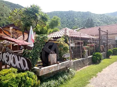 a house with a water fountain in a yard at КръчмЪ при Байката Alpin in Ribarica
