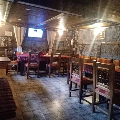 a dining room with wooden chairs and a table at КръчмЪ при Байката Alpin in Ribarica