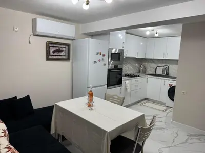 a living room with a table and a kitchen at Guest House Tatiana Studio in Petrich