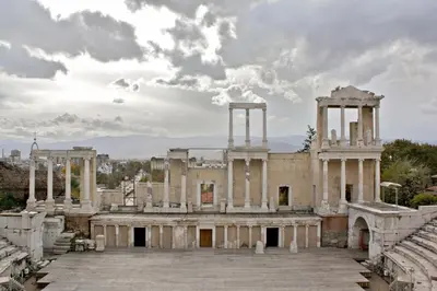 an old building with columns and a cloudy sky at Апартамент Ламартин- в сърцето на Пловдив in Plovdiv