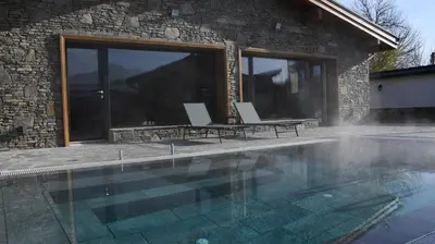 a swimming pool with two chairs next to a house at Къщи за гости Авена и Авена 2 in Banya