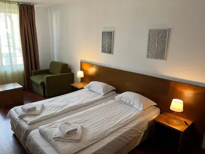 a hotel room with a large bed and a chair at Ski & Relax Apartments in Bellevue Residence in Bansko