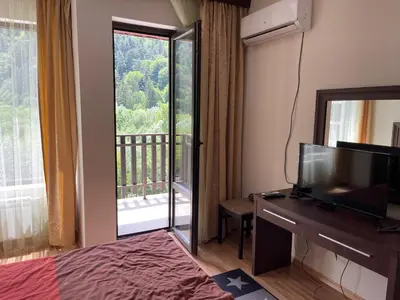 a room with a bed and a television and a balcony at Мия 3 Спа хотел Свети Спас in Velingrad