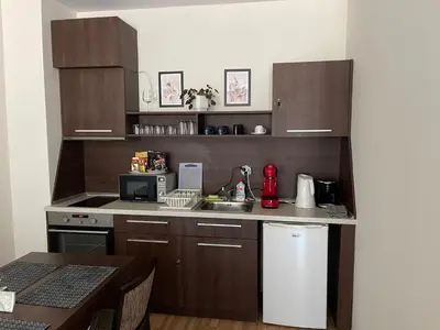 a kitchen with brown cabinets and a sink and a table at Мия 3 Спа хотел Свети Спас in Velingrad