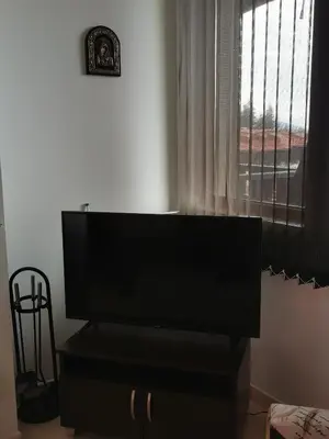 a flat screen tv sitting on a dresser in front of a window at Apartment Sam in Grand Monastery in Pamporovo
