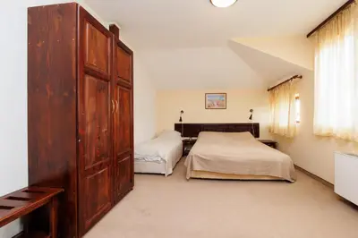 a bedroom with two beds and a large wooden cabinet at Конна база и Къща за гости Дворене in Razlog
