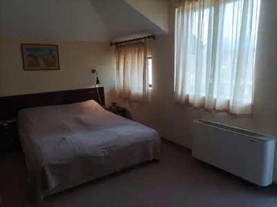 a bedroom with a bed and a window with curtains at Конна база и Къща за гости Дворене in Razlog