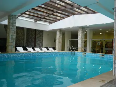 a large swimming pool in a hotel with chairs at Bansko Apartment Predela the One in Bansko