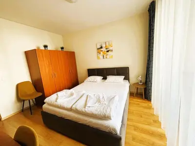 a bedroom with a bed with white sheets and a wooden cabinet at Bansko Apartment Predela the One in Bansko
