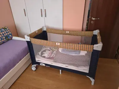 a small crib in a room with a bed at Слънчев апартамент с прекрасна гледка, паркинг. in Smolyan
