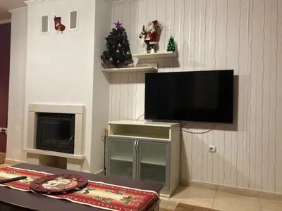 a living room with a television and a christmas tree at Grand Monastery Apartment in Pamporovo