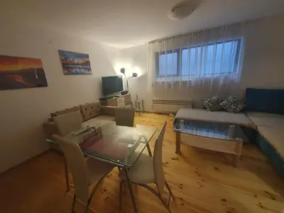 a living room with a couch and a table and chairs at Mila Apartment in Bansko