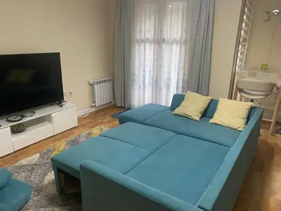 a living room with a blue couch and a flat screen tv at Ski to door at Mountain View 1BR condo Bansko in Bansko