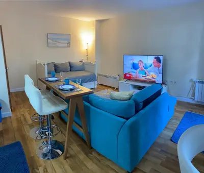 a living room with a blue couch and a tv at Ski to door at Mountain View 1BR condo Bansko in Bansko