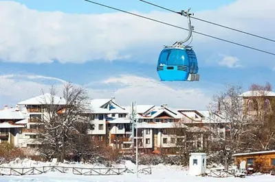 a blue cable car in the snow in front of buildings at Bansko Royal Towers 253 in Bansko