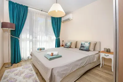 a bedroom with a large white bed with blue curtains at 2BR apartment ,10 minutes walk to TOP Center in Plovdiv