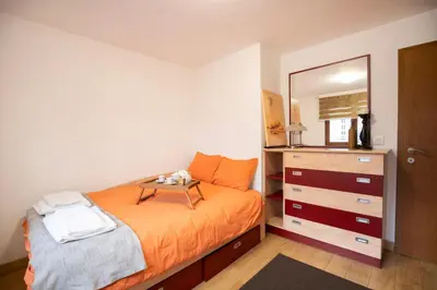 a bedroom with a bed and a dresser with a mirror at Cozy Apartment with Mountain View & Parking in Sofia