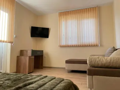 a room with a bed and a tv and a couch at Villa Stoyanovata Kashta in Samokov