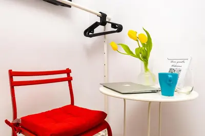 a red chair sitting next to a table with a laptop at House Of History , Rooms in the Main Street Plovdiv in Plovdiv