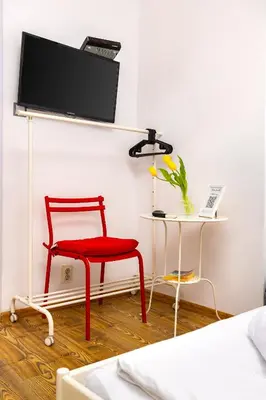 a red chair in a room with a tv on a wall at House Of History , Rooms in the Main Street Plovdiv in Plovdiv
