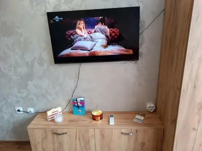 a flat screen tv on a wall above a wooden cabinet at Студио Еми in Chepelare
