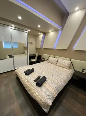 a bedroom with a large bed with two black objects on it at Modern 1BR Apartment with Garden View & Free street parking in Plovdiv