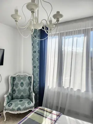 a bedroom with a chandelier and a chair next to a window at Bulgarane House in Govedartsi
