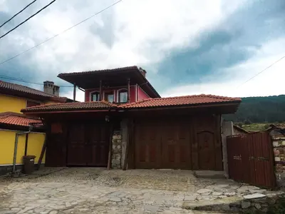 a house with two wooden garage doors in front at Стаи за гости Бащино огнище in Koprivshtitsa