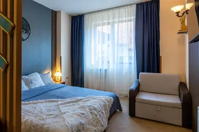 a bedroom with a bed and a chair and a window at Snow Line Suites SLS in Bansko