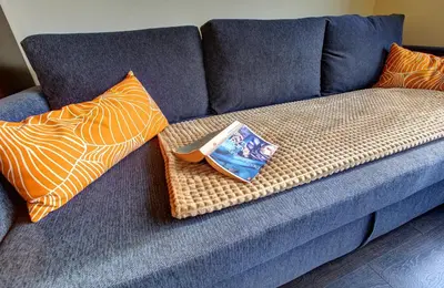 a book is sitting on a blue couch with pillows at 1BD Nest in the heart of a traditional Sofia by Flat Mаnager in Sofia
