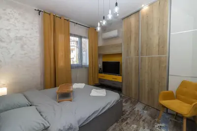 a bedroom with a bed and a chair and a television at Unique Central 1 Bedroom Flat in Sofia