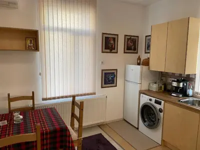 a kitchen with a refrigerator and a table and a washing machine at Дом за Гости Осогово in Kyustendil