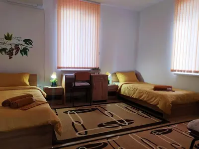 a room with two beds and a desk and windows at Дом за Гости Осогово in Kyustendil