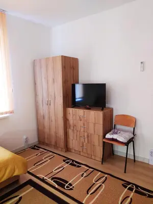 a bedroom with a tv and a chair and a cabinet at Дом за Гости Осогово in Kyustendil