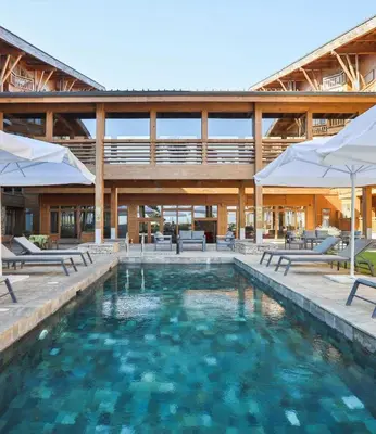 a pool with chairs and umbrellas in front of a building at Pirin Golf Private Apartments & Studios in Razlog