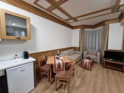 a kitchen and living room with a table and chairs at Pirin Golf Private Apartments & Studios in Razlog